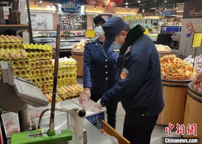 圖為疫情期間，甘肅嘉峪關(guān)市場監(jiān)管局工作人員檢查蔬菜市場?！?柴佳楠 　攝