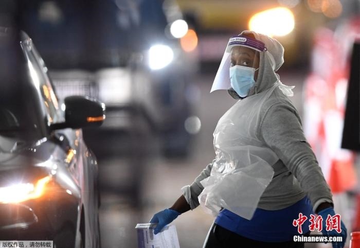 當(dāng)?shù)貢r(shí)間12月18日，英國(guó)政府公布的數(shù)據(jù)顯示，當(dāng)天英國(guó)新增奧密克戎毒株感染病例10059例。鑒于奧密克戎毒株感染病例激增，住院人數(shù)不斷上升，倫敦市長(zhǎng)宣布倫敦進(jìn)入“重大事故”狀態(tài)。圖為倫敦的一個(gè)免下車檢測(cè)中心，一名醫(yī)務(wù)工作者正準(zhǔn)備對(duì)司機(jī)進(jìn)行核酸檢測(cè)。