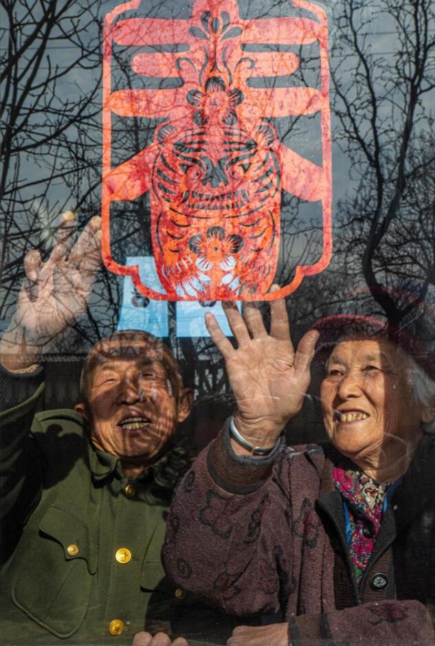 臘月里，霍州市師莊鄉(xiāng)馮南垣村村民師榮光(左)在災(zāi)后重建的新家里貼窗花。(霍州市委宣傳部供圖)