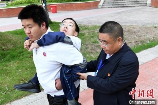 朱金祥背著鐘華強去教室上課的路上，也經常碰到值班的校領導和老師前來搭把手。 卓忠偉 攝