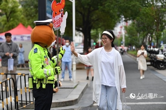 6月7日上午9時(shí)，隨著鈴聲的響起，2023年江西高考正式開考，江西省的53.57萬考生以縣（區(qū)）為單位隨機(jī)安排在全省256個(gè)考點(diǎn)、18968個(gè)考場(chǎng)參加高考。圖為“小熊交警”和考生擊掌鼓勵(lì)。 人民網(wǎng)記者 時(shí)雨攝