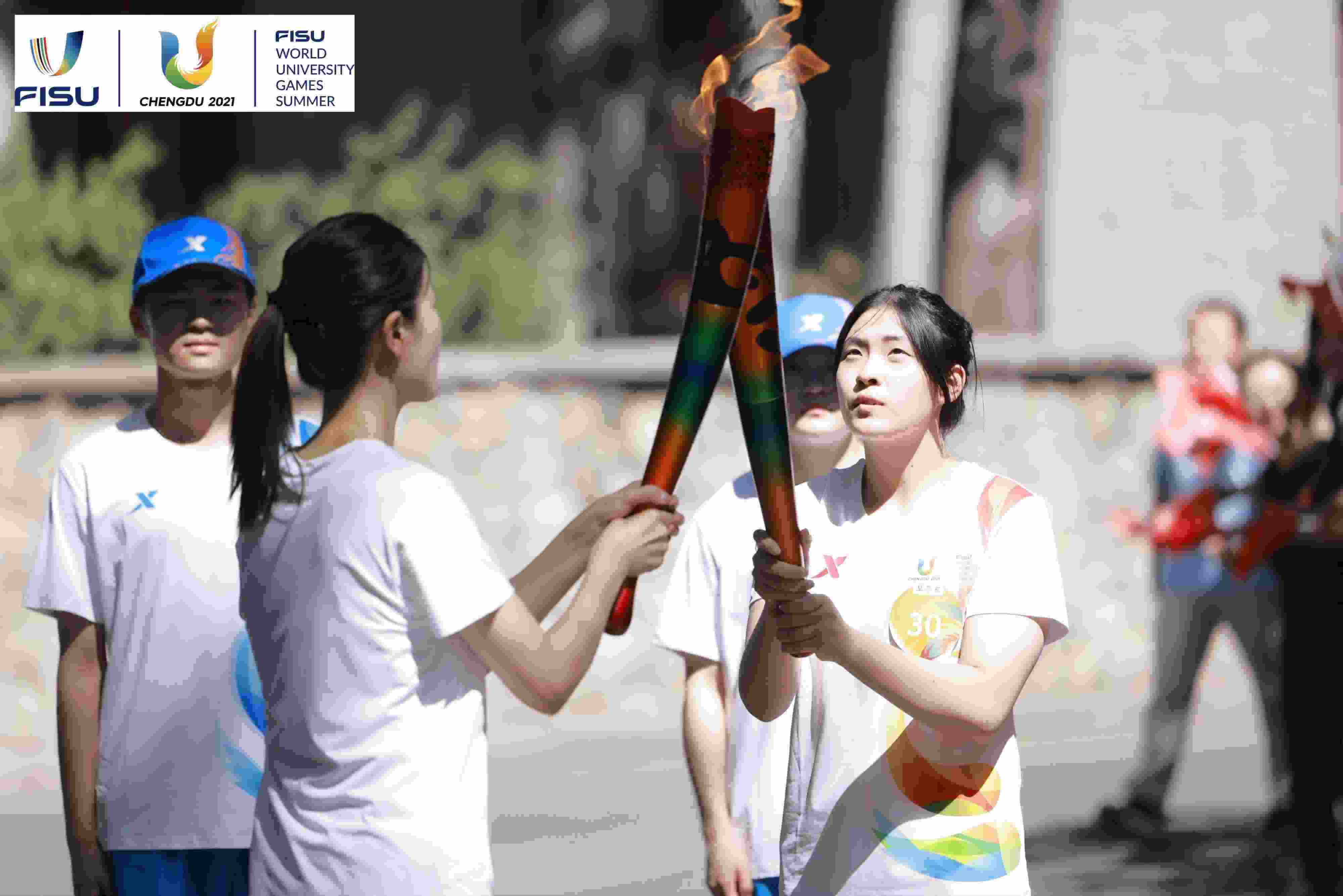 兩名大運會火炬手進行火炬?zhèn)鬟f。 圖片來源：成都大運會執(zhí)委會供圖