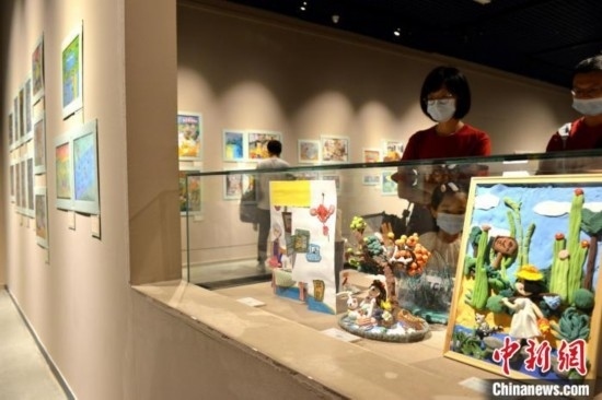 圖為家長(zhǎng)帶著孩子參觀展覽。呂明 攝