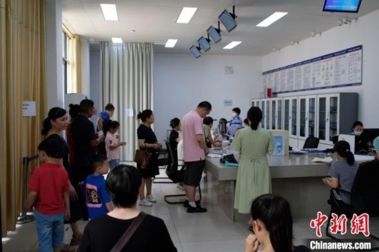 圖為在戶籍辦證廳內(nèi)排隊(duì)等待的家長和孩子。劉俊聰 攝