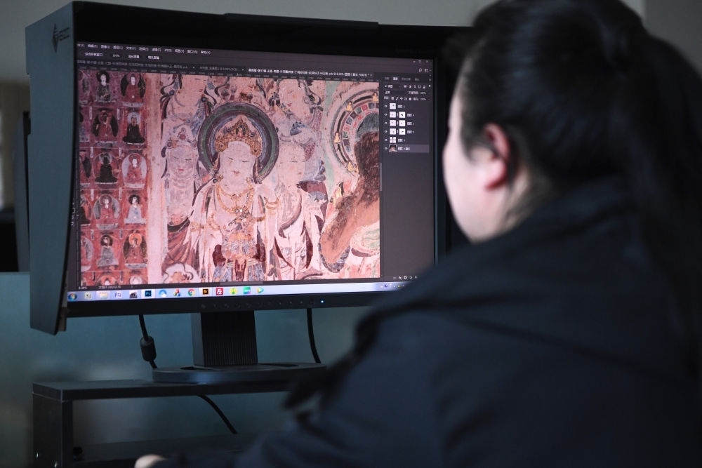 敦煌研究院文物數(shù)字化保護團隊圖像處理人員年海麗在拼接壁畫圖像（2023年4月25日攝）。數(shù)字化探索為莫高窟的保護與傳承開辟了全新路徑，數(shù)字技術(shù)讓敦煌文物走出洞窟，跨出國門，走向“永久保存、永續(xù)利用”。新華社記者 陳斌 攝