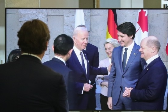 2022年3月24日，在比利時布魯塞爾的北約總部，一名男子觀看屏幕上美國總統(tǒng)拜登（右四）、歐盟委員會主席馮德萊恩（右三）、加拿大總理特魯多（右二）、德國總理朔爾茨（右一）出席七國集團峰會合影儀式的畫面。新華社記者鄭煥松攝