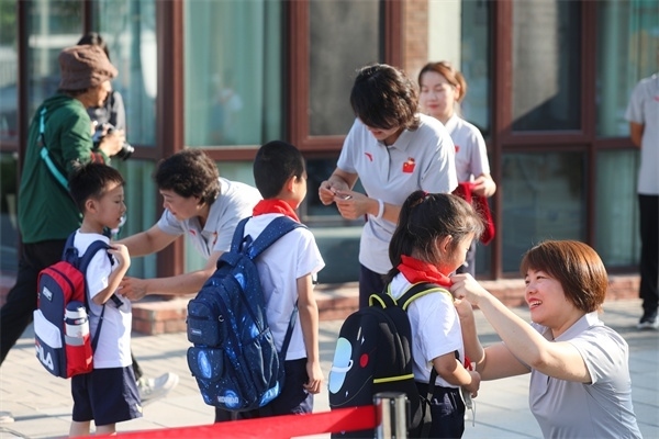 8月30日，雄安史家胡同小學(xué)學(xué)生體驗學(xué)校生活。老師為學(xué)生佩戴?；?。