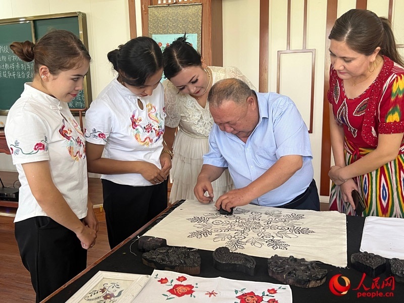 國家級非物質(zhì)文化遺產(chǎn)模戳印花布技藝傳承人吾吉阿西木?吾舒爾展示模戳印花布的制作過程。人民網(wǎng)記者 常雪梅攝