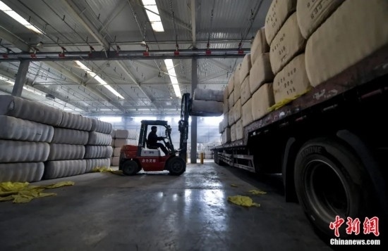 新疆喀什綜合保稅區(qū)，喀什啟路國(guó)際貿(mào)易有限公司的倉(cāng)庫(kù)內(nèi)，工人正在裝載從塔吉克斯坦和烏茲別克斯坦進(jìn)口的棉花。劉新攝
