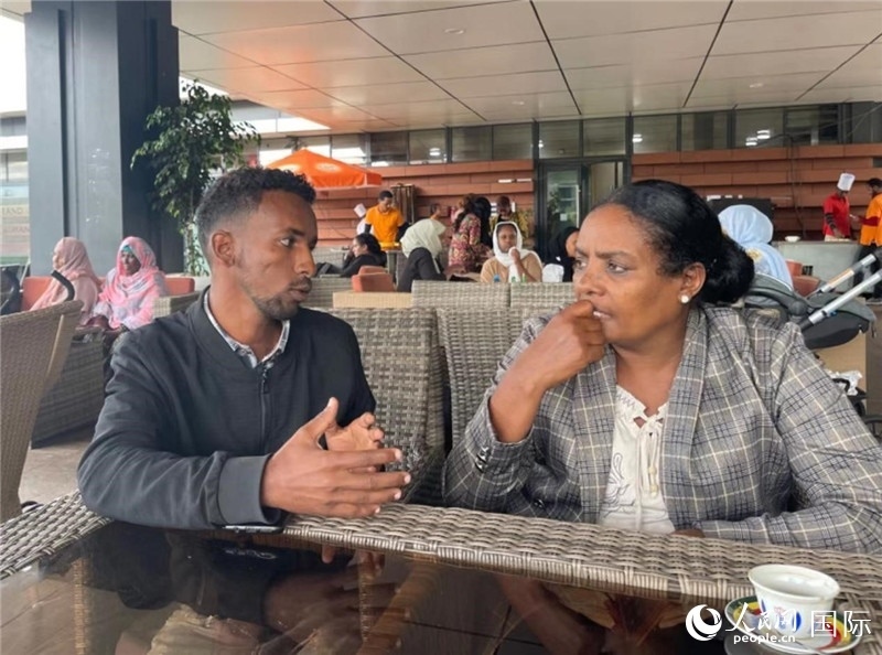 約漢斯（圖左）與德貝拉在友誼廣場咖啡廳交談。人民網記者 趙艷紅攝