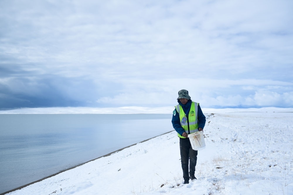 2021年10月20日，在青海省果洛藏族自治州瑪多縣扎陵湖鄉(xiāng)勒那村，三江源國(guó)家公園黃河源園區(qū)生態(tài)管護(hù)員在扎陵湖邊撿拾垃圾。新華社記者 張龍 攝