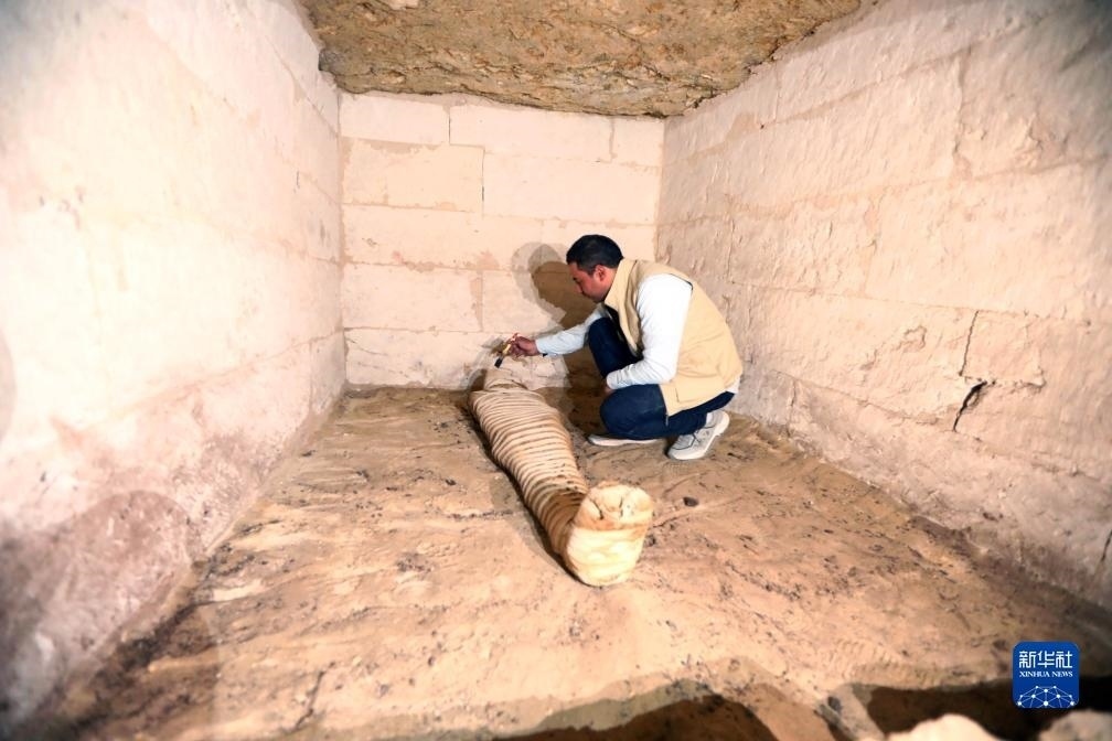 10月15日，在埃及明亞省考古現(xiàn)場(chǎng)，考古人員清理一座石鑿墓中的木乃伊。新華社發(fā)（艾哈邁德·戈馬攝）