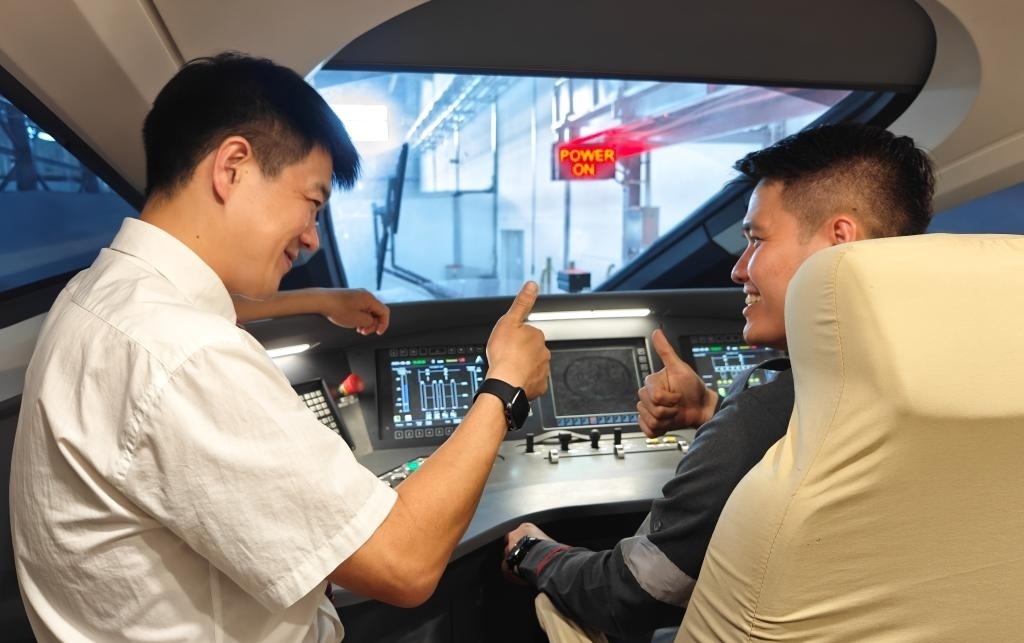 8月25日，在印度尼西亞萬隆的雅萬高鐵德卡魯爾動車所內(nèi)，中國師傅穆振（左）在向印尼火車司機塞蒂亞萬講解動車組出庫前的上電作業(yè)。