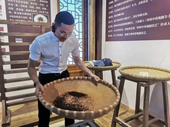 2023“一帶一路”媒體合作論壇聯(lián)合采訪團團員在非遺文化展示館體驗中藥炮制技藝。（本報記者 黃超攝）