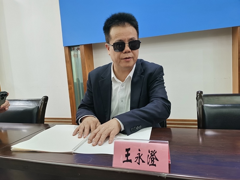 全國人大代表王永澄正在閱讀盲文版代表建議答復(fù)。本報記者 張 璁?dāng)z