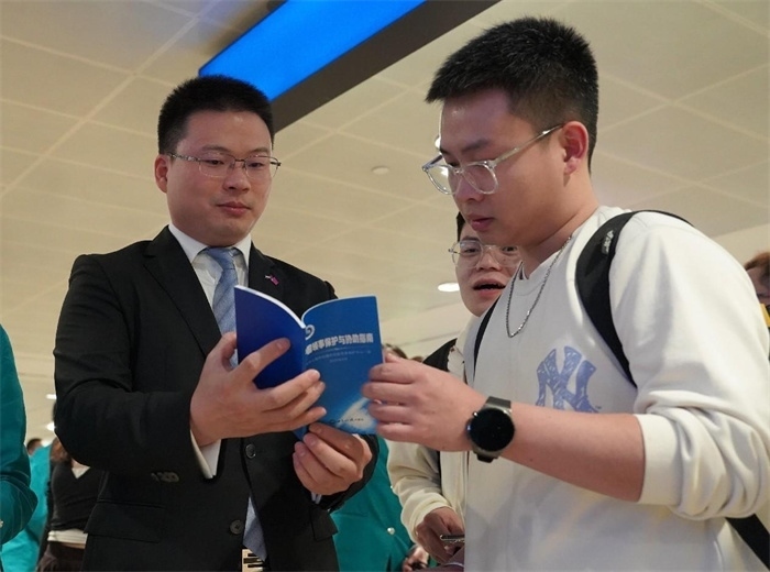 工作人員（左一）在發(fā)放《中國領(lǐng)事保護(hù)與協(xié)助指南》。 中國駐迪拜總領(lǐng)事館供圖