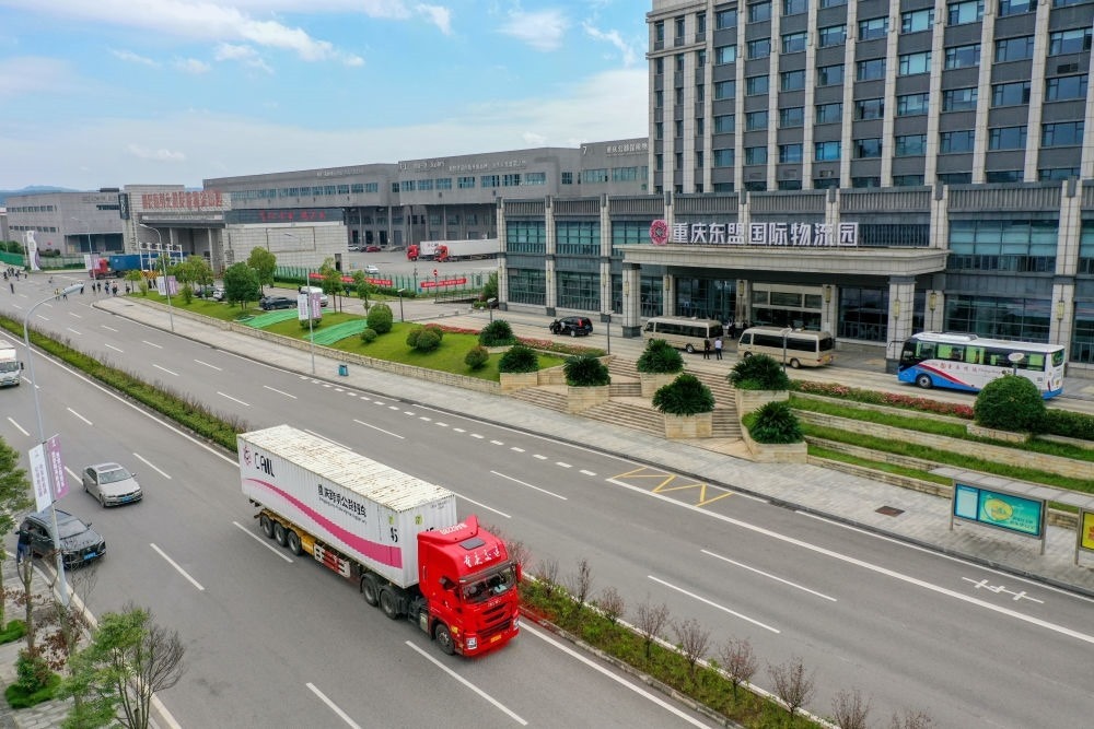 2023年10月11日，滿載筆記本電腦配件、發(fā)電機(jī)組件等產(chǎn)品的西部陸海新通道跨境公路班車從重慶南彭公路保稅物流中心駛出，將途經(jīng)廣西憑祥，直達(dá)越南（無人機(jī)照片）。新華社記者 黃偉 攝