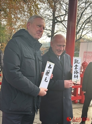 柏林市長韋格納（右）、動物園監(jiān)事會主席布魯克曼（左）手持中國文化中心工作人員現(xiàn)場手書的中文名字。人民網(wǎng)記者 徐馨攝