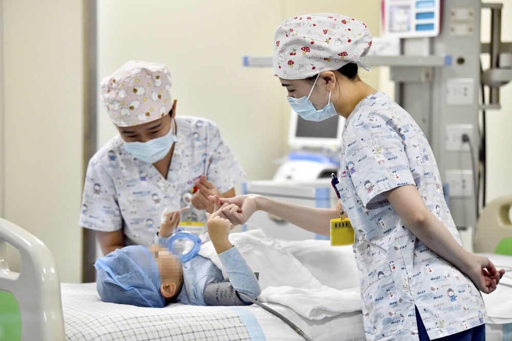 在山東省棗莊市婦幼保健院兒童ICU病房，醫(yī)護人員為完成靶向治療藥物諾西那生鈉的4歲脊髓性肌萎縮癥患兒加油鼓勁（2022年1月1日攝）。諾西那生鈉注射液是我國首個獲批治療脊髓性肌萎縮癥的進口藥物，2019年進入中國市場時，每針價格近70萬元。在2021年國家醫(yī)保目錄藥品談判中，以3.3萬元每針的價格進入新版醫(yī)保藥品目錄。新華社記者 郭緒雷 攝