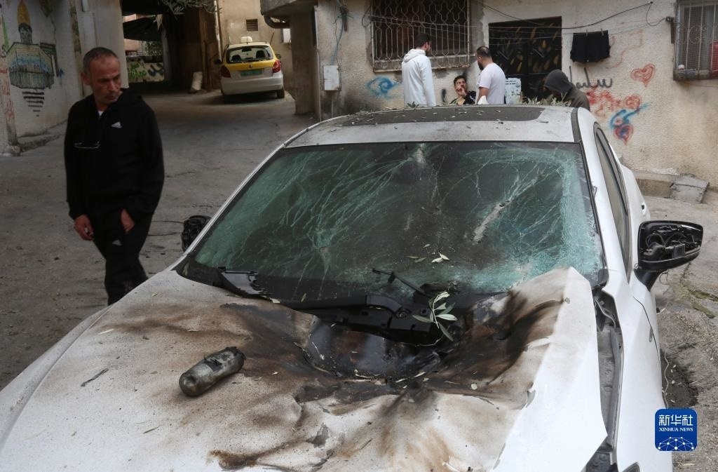 12月17日，在約旦河西岸城市圖勒凱爾姆附近的一處難民營，人們查看在沖突中損毀的車輛。新華社發(fā)（尼達(dá)爾·艾仕塔耶?dāng)z）