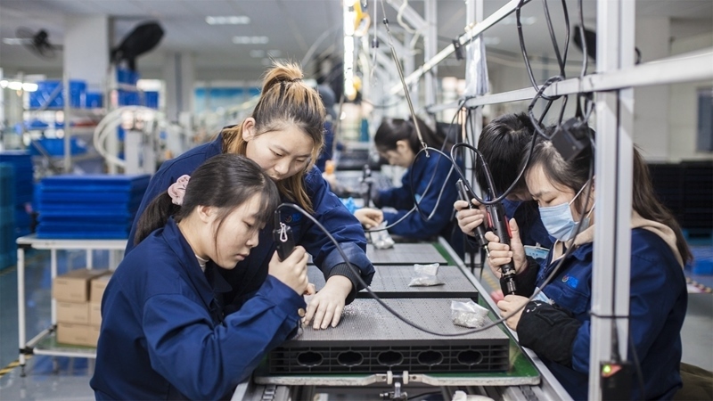 在新亞勝光電的產(chǎn)品線上，工人正進行產(chǎn)品組建和安裝布線。受訪者供圖