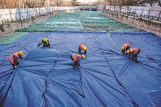 1月3日，房山區(qū)東風(fēng)街道，工人正在修復(fù)的河道內(nèi)給混凝土鋪設(shè)保溫布。