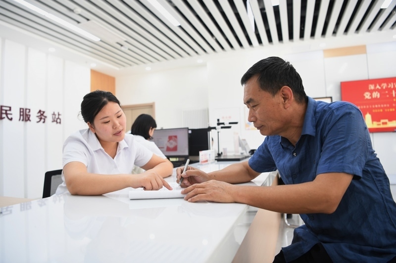 2023年5月23日，河北雄安新區(qū)容東片區(qū)南文營社區(qū)居民（右）在社區(qū)便民服務站辦理業(yè)務。