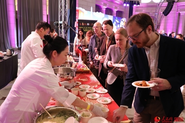 當(dāng)?shù)貢r(shí)間3月7日晚，華盛頓聯(lián)合車站廣場(chǎng)舉行駐美使團(tuán)“使館主廚挑戰(zhàn)賽”。圖為當(dāng)?shù)孛癖娫谥袊古_(tái)前體驗(yàn)中國美食。人民網(wǎng)記者 李志偉攝