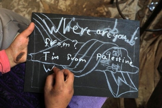 2023年12月28日，一名學(xué)生在加沙地帶南部城市拉法一所學(xué)校的臨時(shí)教室中寫下“我來自巴勒斯坦”的字樣。新華社發(fā)（里澤克·阿卜杜勒賈瓦德攝）