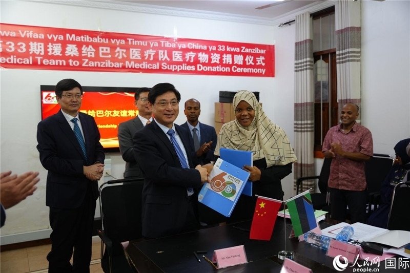 江蘇省蘇北人民醫(yī)院黨委書記束余聲與桑衛(wèi)生部首席秘書哈比巴交換捐贈書。中國援桑醫(yī)療隊供圖