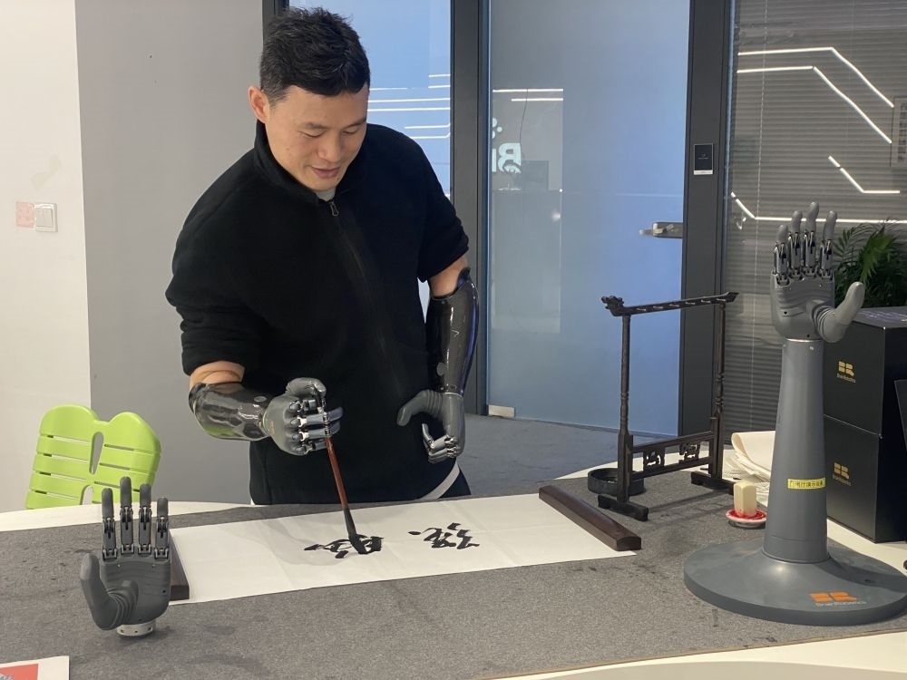 2024年3月29日，在浙江強腦科技有限公司展廳內，失去雙手的產品體驗官倪敏成依靠智能仿生手寫毛筆字。新華社記者 魏一駿 攝