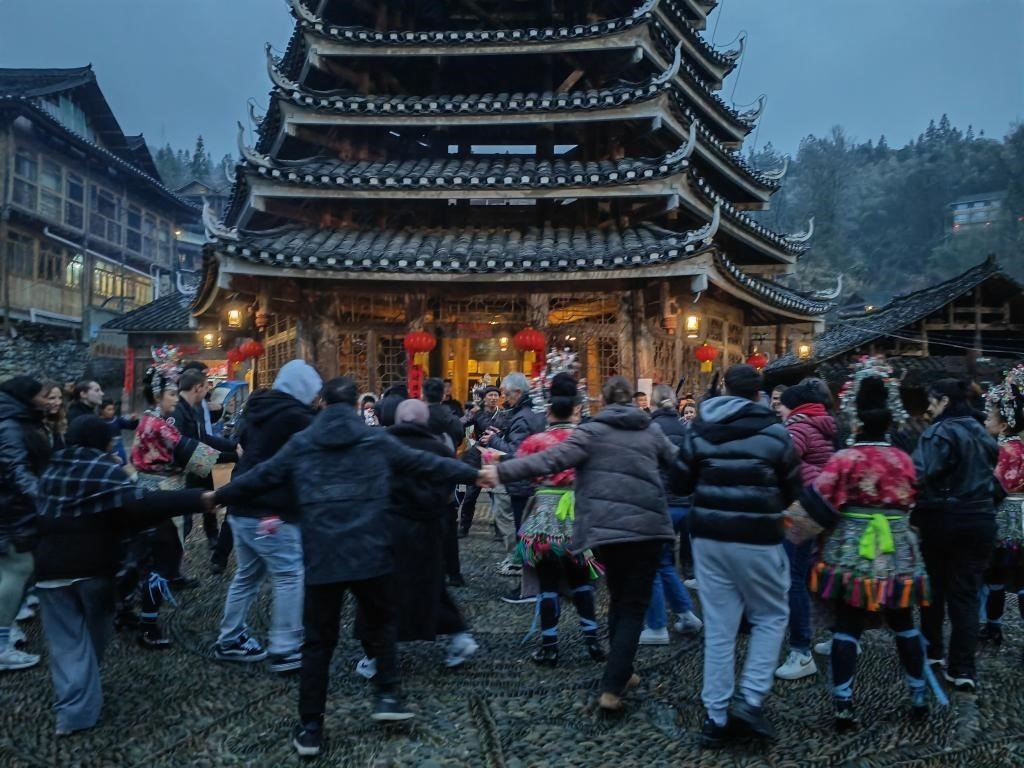 法國青年與當?shù)卮迕駹渴痔?。新華社記者 羅羽 攝