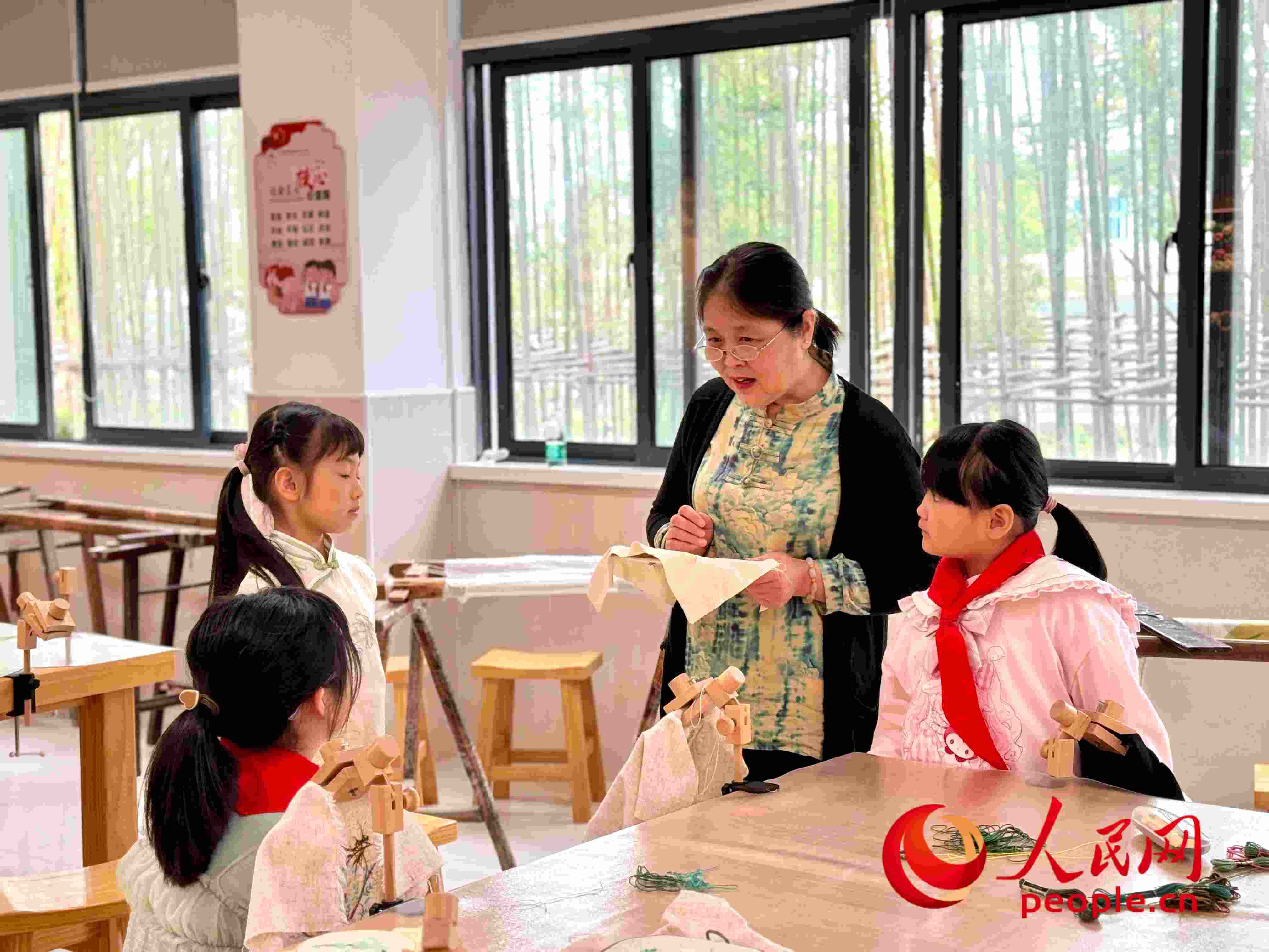 顧建珍（左三）在教孩子們刺繡知識。人民網(wǎng) 周靜圓攝