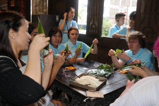 6月9日，美國青年代表在重慶永川松溉古鎮(zhèn)體驗包粽子。新華社記者 周思宇 攝