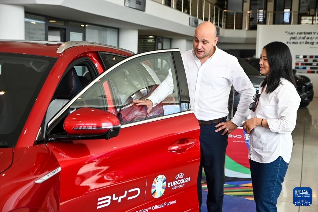 2024年5月29日，在馬耳他比爾基卡拉，馬耳他哈桑-扎米特汽車公司首席執(zhí)行官德古阿拉（左）介紹一輛比亞迪純電動(dòng)汽車。新華社發(fā)（喬納森·博格 攝）