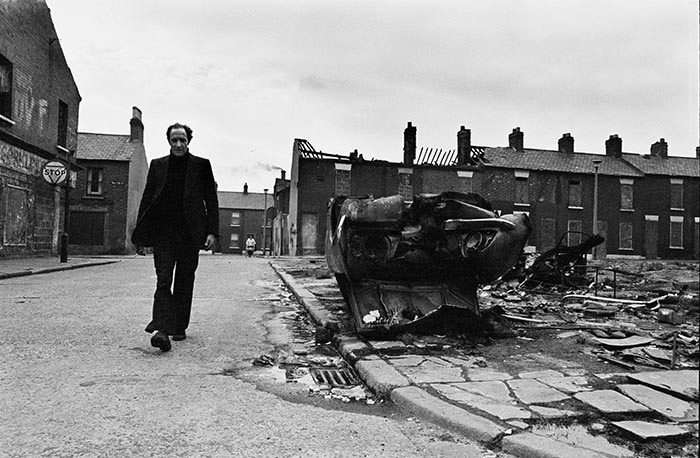 20世紀(jì)60年代末，北愛(ài)爾蘭爆發(fā)了長(zhǎng)達(dá)30多年的“社區(qū)暴力事件”。圖為1972年3月21日，一名居民走過(guò)被大火燒毀的房屋和汽車殘骸。