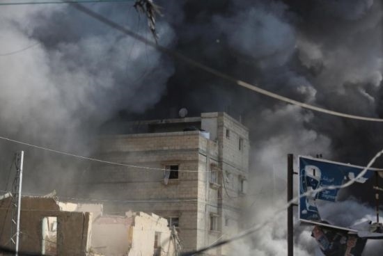 7月21日，在加沙地帶中部的努賽賴特難民營(yíng)，遭以軍空襲的建筑冒出滾滾濃煙。新華社發(fā)（馬爾萬(wàn)·達(dá)烏德攝）