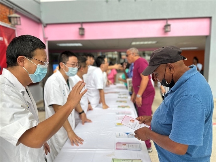 援圭醫(yī)療隊隊員們在啟動儀式上為當?shù)孛癖姺职l(fā)宣傳手冊。中國援助圭亞那醫(yī)療隊供圖