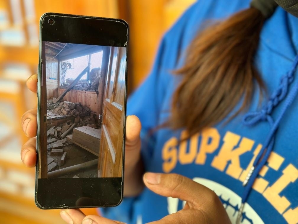 圖為7月17日拉毛東智在手機上找出地震后房屋受損的照片。新華社記者 張子琪 攝