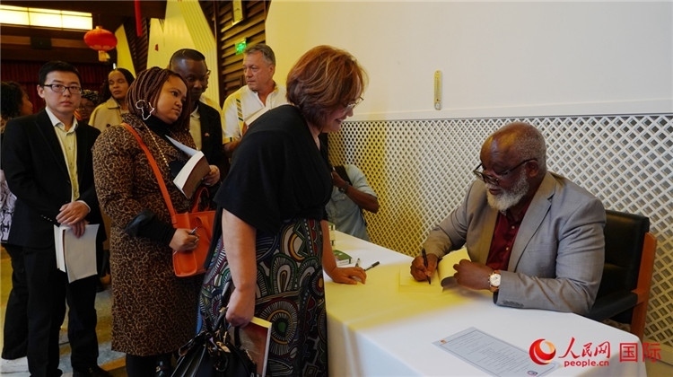 譚哲理在活動現(xiàn)場簽名贈書。人民網(wǎng) 劉暢攝