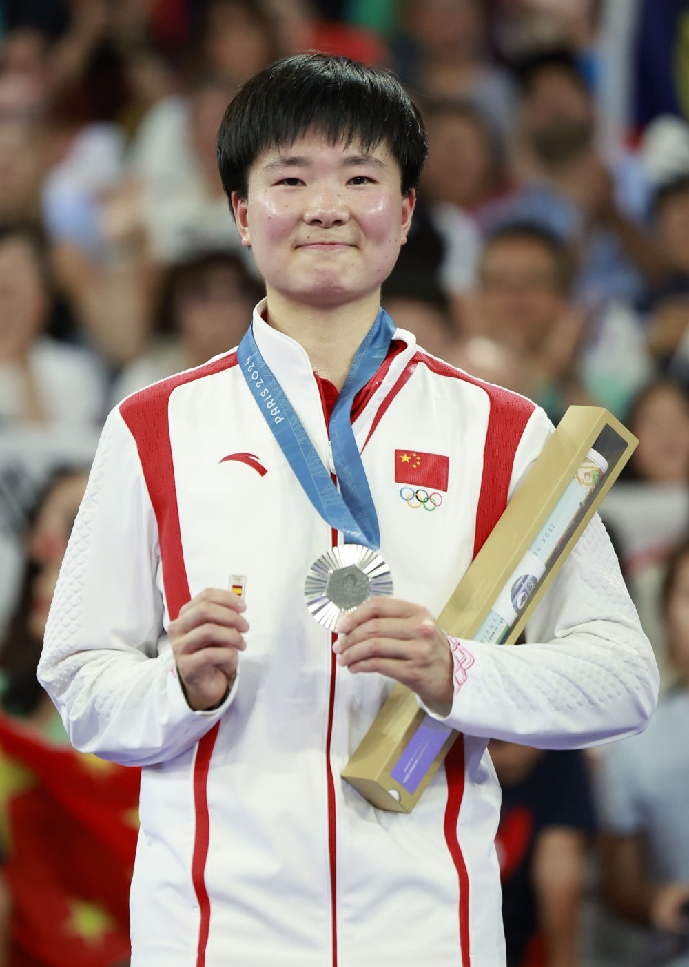 巴黎奧運會羽毛球女子單打亞軍、中國選手何冰嬌在頒獎儀式上一手握著銀牌，一手握著西班牙奧委會徽章（2024年8月5日攝）。新華社記者 任正來 攝