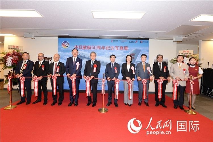 與會(huì)嘉賓共同為中日通航50周年紀(jì)念圖片展開幕剪彩。馮學(xué)敏攝