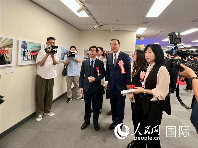 中國國際航空日韓地區(qū)支社支社長馮力為中國駐日本大使館臨時(shí)代辦施泳等嘉賓介紹展出圖片。人民網(wǎng) 許可攝
