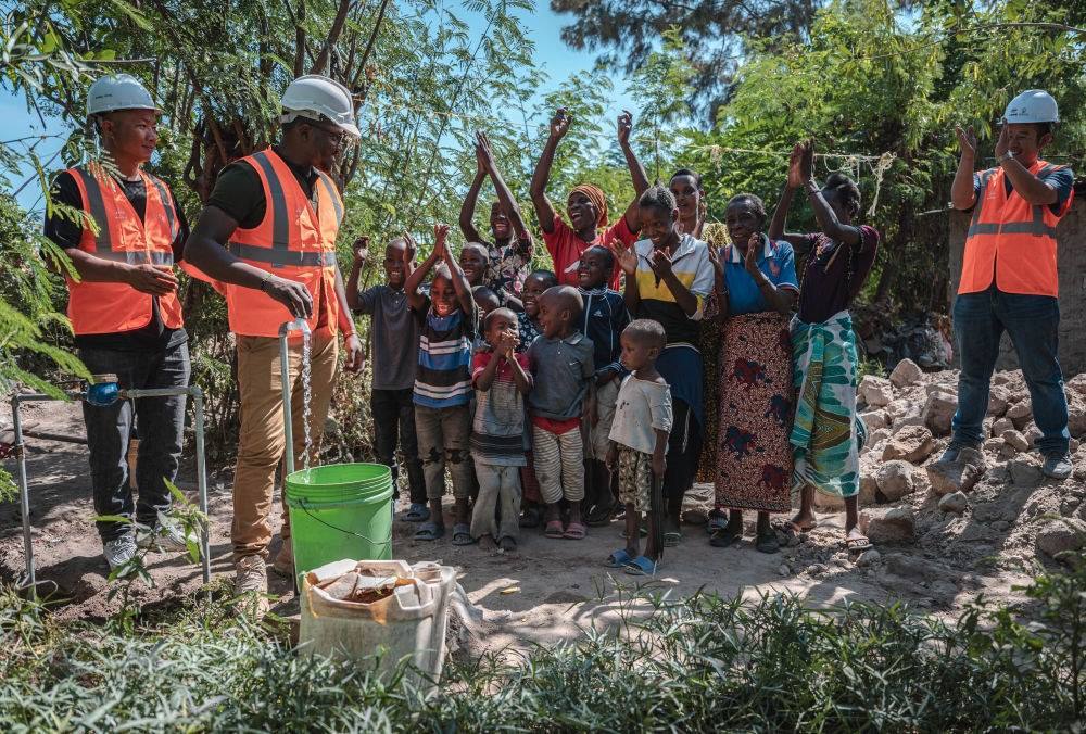 2023年6月13日，在坦桑尼亞姆萬扎省米松圭，工作人員接通水管后贏得當(dāng)?shù)鼐用窆恼茪g呼。新華社記者 王冠森 攝