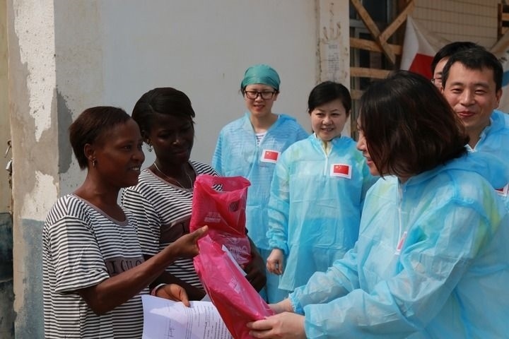 2015年4月4日，在位于塞拉利昂首都弗里敦市郊的中塞友好醫(yī)院埃博拉診療中心，中國(guó)第四批援塞醫(yī)療隊(duì)副隊(duì)長(zhǎng)邵蔚（右前）向被治愈的埃博拉出血熱患者贈(zèng)送禮物。新華社發(fā)（祖榮強(qiáng) 攝）