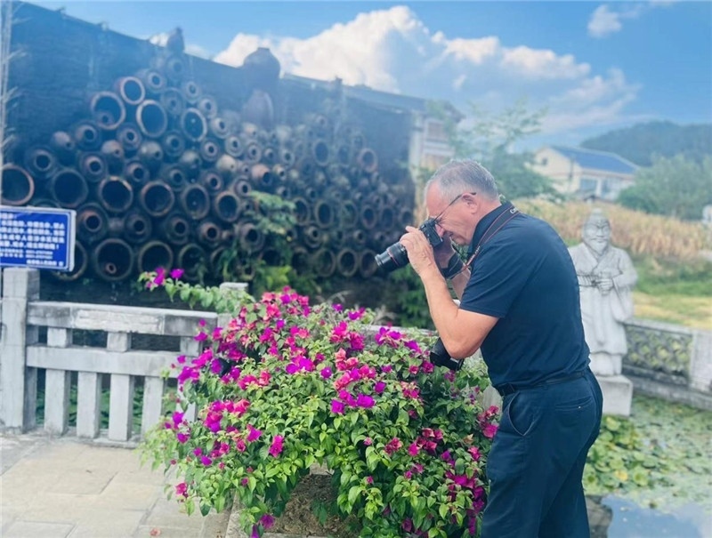 遠(yuǎn)處黔北民居錯落有致，近處一只黑色的蝴蝶穿梭于粉紫色三角梅花叢間隙，與俄羅斯“大歐亞”總編輯弗拉基米爾·別列日內(nèi)赫的鏡頭玩起了捉迷藏，“你追我逃，不亦樂乎”。（張亞欣攝）