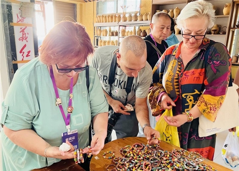 歐亞媒體考察團(tuán)成員在母氏陶藝館內(nèi)挑花了眼，色彩絢麗、質(zhì)地均勻的陶藝手串讓他們愛不釋手?！斑@里的東西都太實惠了！”塔吉克斯坦《索格特真理報》政論部主任娜塔利婭·多羅費耶娃說?；宓奶厣a(chǎn)品物美價廉，讓考察團(tuán)成員為家人好友買到了心儀的禮物，也為此次以四川成都為起點，路經(jīng)南充、廣安至貴州遵義的考察行程畫上了圓滿句號。（張亞欣攝）
