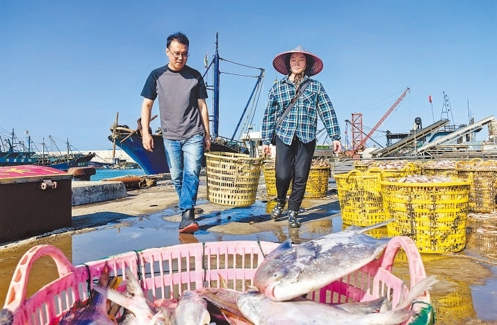 許小斌（左）和漁民一起搬運(yùn)海鮮。本報(bào)記者 付 文攝