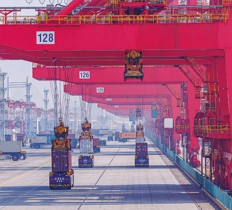 共建“一帶一路”國家在工作制度對接、技術(shù)標準協(xié)調(diào)、檢驗結(jié)果互認等方面強化合作、統(tǒng)一標準，貿(mào)易自由化便利化水平不斷提升。上海洋山港海關(guān)對接共建國家進出口貨物相關(guān)標準，推動通關(guān)一體化方式申報，提升通關(guān)效率。圖為無人駕駛的全自動導(dǎo)引車在洋山港穿梭往來，搬運集裝箱。王初 攝