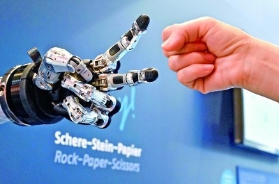 在德國漢諾威工博會上，參觀者與一款智能機器人進行“石頭剪子布”游戲。新華社發(fā)